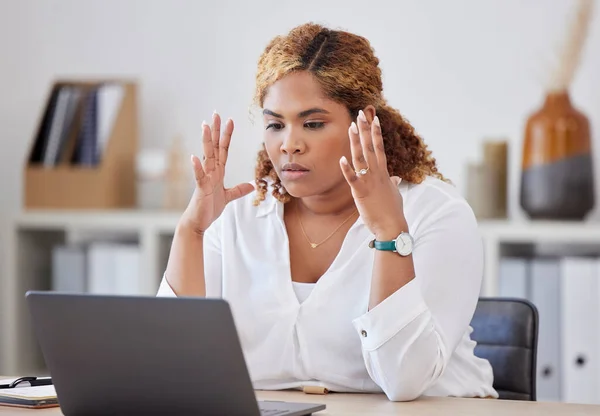 Young stressed mixed race businesswoman looking angry while working on a laptop alone at work. One upset hispanic businesswoman stressing while working on a computer at a desk in an office.