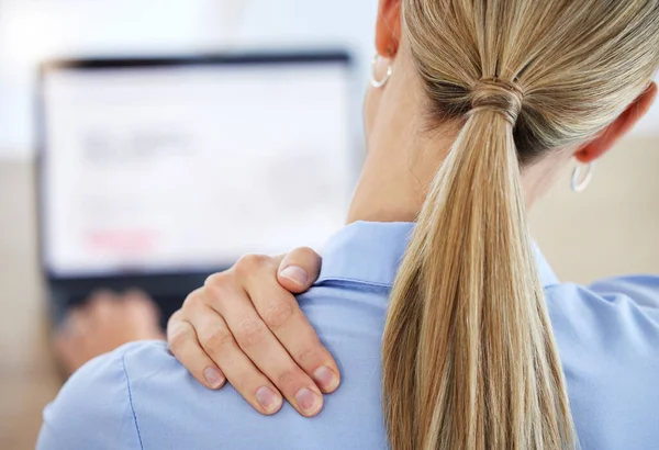 Young business woman rubbing neck in pain while working in office from behind.