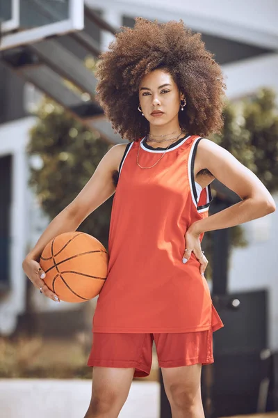 Mixed race woman posing on a basketball court. Beautiful basketball player posing confidently outside.