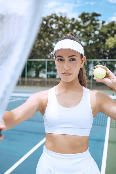 Confident young female tennis player holding a tennis racket and ball. Hispanic woman ready for her tennis match at the club. Sportswoman ready for tennis practice.