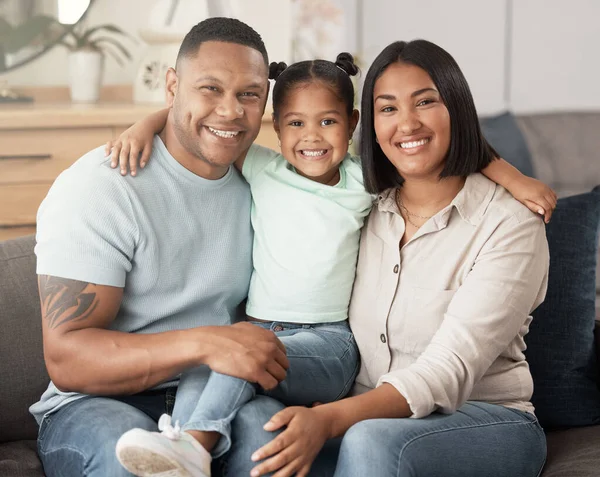 Portrait of a mixed race family of three relaxing on the sofa at home. Loving black family being affectionate on the sofa. Young couple bonding with their daughter at home.