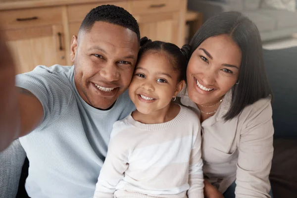 Portrait of a mixed race family of three relaxing on the sofa at home. Loving black family being affectionate on the sofa. Young couple bonding with their daughter at home.