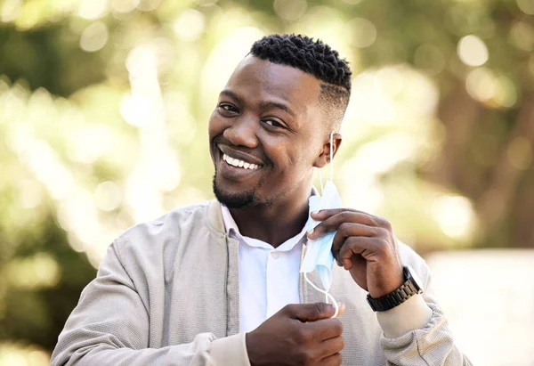 Portrait of a young businessman standing in the street in the city smiling and looking happy on a sunny day. African american male expressing happiness on his face.