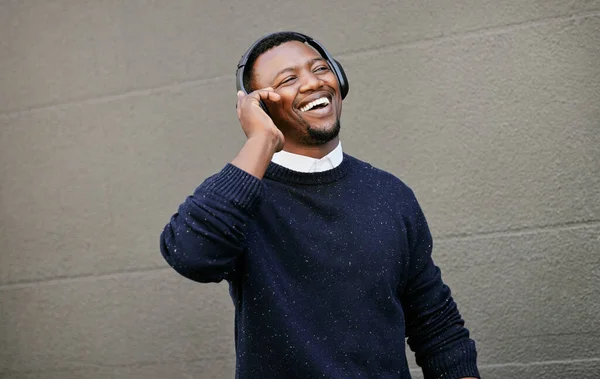 African american male on a phone call with his mobile device outside a building during the day while smiling Young black male talking on a phone while commuting to work.