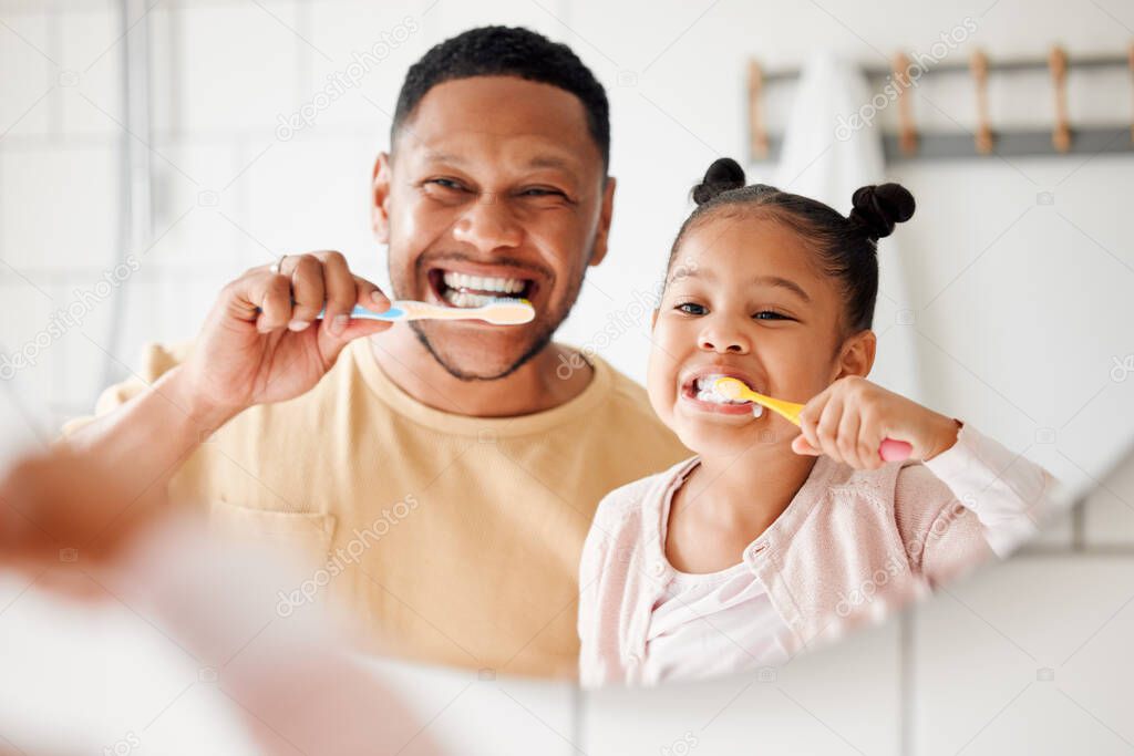 Happy mixed race father and daughter brushing their teeth together in a bathroom at home. Single African American parent teaching his daughter to protect her teeth.