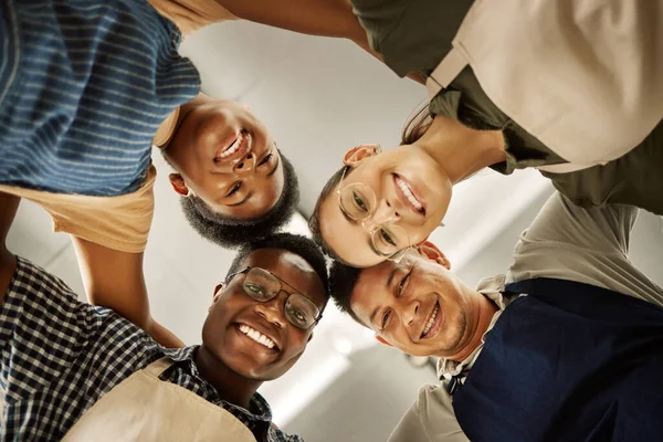 Portrait of group of fashion designers huddles together. Happy tailors united in a circle from below. Diverse businesspeople collaborating together.Professional entrepreneurs together in a circle.