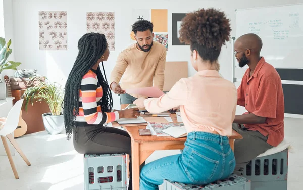 Group of diverse businesspeople having a meeting in a modern office at work. Young hispanic businessman looking at an idea on paper in a boardroom with colleagues. Businesspeople planning together.