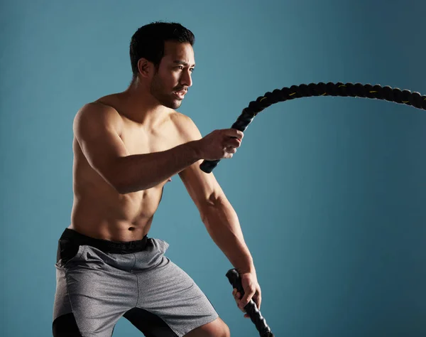 Handsome Young Hispanic Man Training Battle Ropes Studio Isolated Blue — Stockfoto