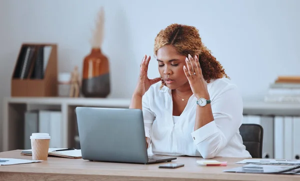 Stressed African American businesswoman making a mistake while using her laptop in the office. Professional black woman feeling pressured while using technology. Creative entrepreneur with a headache.