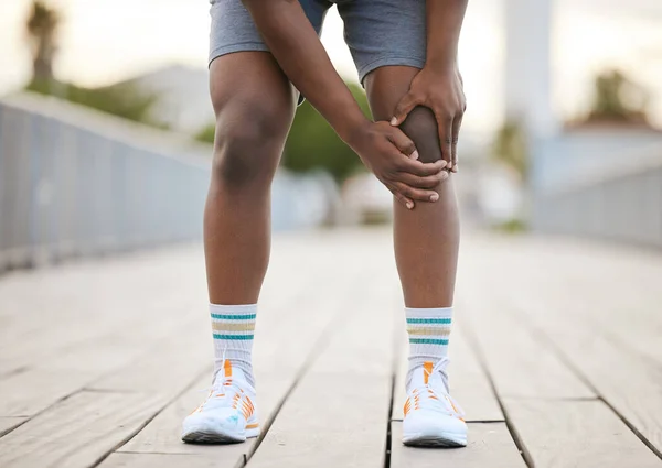 一个因运动而疼痛的男人抓住他的膝盖 一位非洲裔美国人慢跑者弯下腰来 疼痛地抓住他的膝盖 — 图库照片