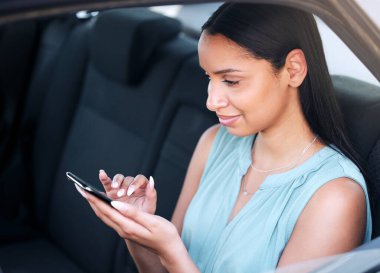 Genç, güzel, melez bir iş kadını arabada otururken telefona mesaj yazıyor. Mutlu İspanyol kadın telefonunu tutarken ve arabada tek başına otururken sosyal medya kullanıyor..