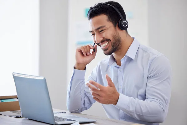 A happy man working in a call center. Operator using a laptop and headset, consulting online or making a video call. A male customer support agent or virtual assistant meeting over video conference.