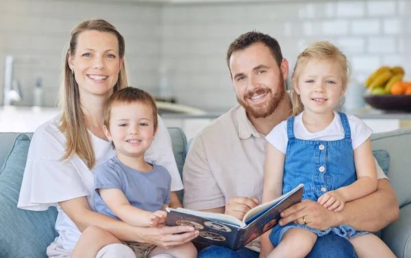 Portrait of young parents with children reading a book, caucasian family of four smiling and enjoying a story. Cheerful couple teaching their two children how to read while sitting on a sofa.