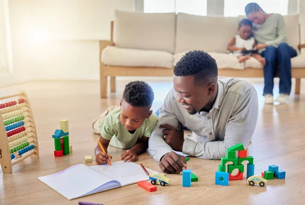 年轻快乐的非洲裔美国父亲坐在家里的地板上帮助他的儿子做作业 小男孩专注于学习和做一件事 小男孩儿在看书 — 图库照片