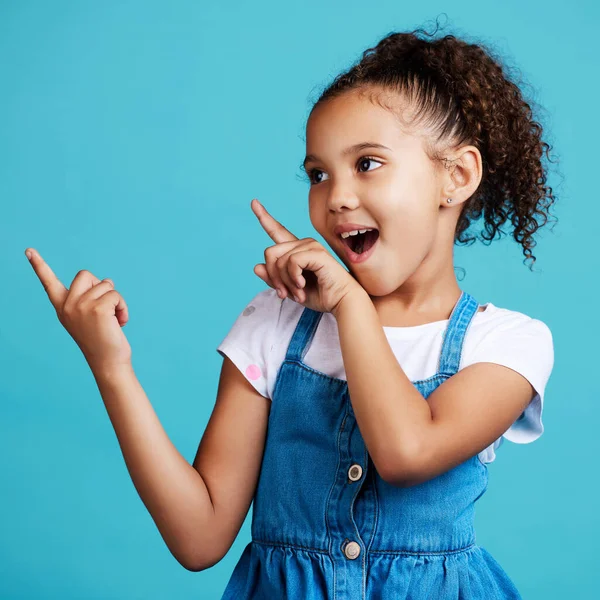 Shot Adorable Little Girl Pointing Something While Standing Blue Background — Foto Stock