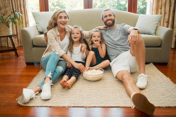 年轻的心满意足的白人家庭坐在休息室的地板上吃爆米花 一起看电影 可爱的小女孩在家里和父母一起看电视 — 图库照片