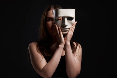 Studio shot of a woman hiding behind a blank mask.
