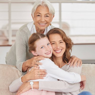 Portrait of a grandmother relaxing with her daughter and mother. Little girl bonding with her parent and grandparent in the living room at home. Three generations spending time together.