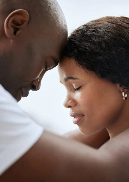 Closeup of a young african american married couple standing face to face with their foreheads touching together. Black man and woman in a loving relationship sharing intimate moment with eyes closed.