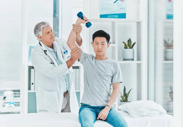 Shot of a mature doctor testing his patients strength.