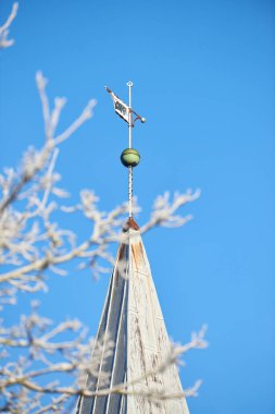 Spire of the church above the trees. Church spires against the cloudy sky in a blue sky. Close up of a spire in an autumn season with a clear sky in the background. A branch of a tree without leaves clipart
