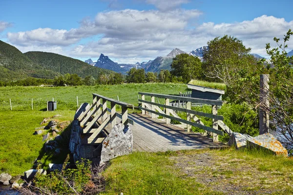 Landscape of wooden bridge in remote green countryside of Bodo in Nordland, Norway. Infrastructure and built crossing in eco meadow and environment fields. Toursim and exploring nature during the day.
