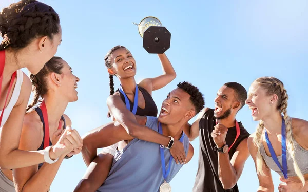 Group of a young fit diverse team of athletes celebrating their victory with a golden trophy. Team of active happy athletes rejoicing after winning an award or trophy after a competitive race.