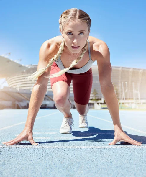 Serious female athlete at the starting line in a track race competition at the stadium. Fit sportswoman mentally and physically prepared to start running at the sprint line or starting block.