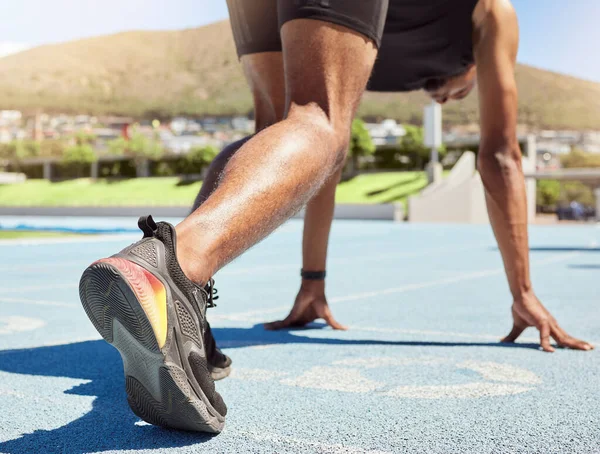 Close up of an athlete getting ready to run track and field with his feet on starting blocks ready to start sprinting. Close up of a man in starting position for running a race on a sports track.