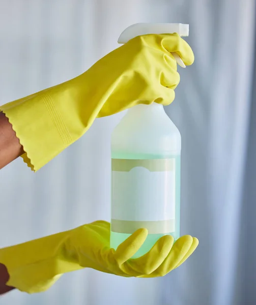 Closeup of a woman holding a cleaning product while tidying her apartment with copyspace. A busy domestic cleaner wearing latex gloves and holding an unlabelled organic agent, hygienic and fresh.