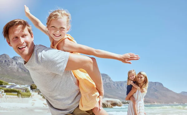 Smiling family with daughters on the beach. Happy man and woman bonding with young adorable girls on holiday. Cute siblings pretending to fly while being carried by their mother and father outside.