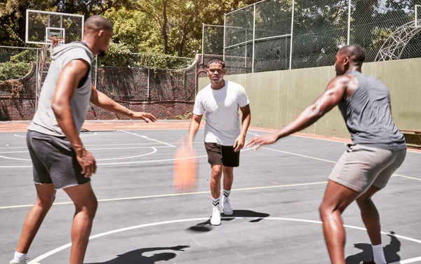 Three african american men playing basketball on a court outdoors. Black man and his sporty friends being athletic outside. Group of basketball players competing in a match or game for recreation fun.