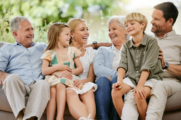Happy and smiling multi generation caucasian family sitting close together on the sofa at home. Happy adorable children bonding with their mother, father, grandfather and grandmother on a weekend.