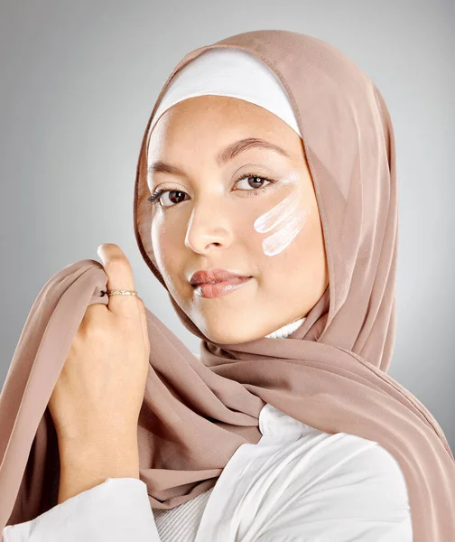 穆斯林妇女的肖像 使用面部保湿霜 防晒霜或乳液隔离在灰色工作室背景与版权空间 年轻女性在做护肤活动时戴头巾或头巾 — 图库照片