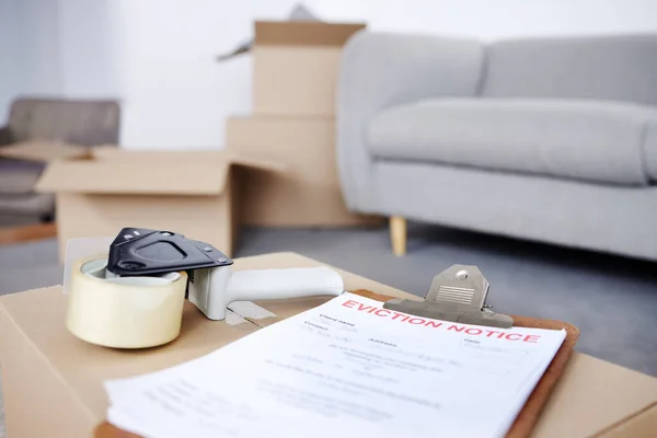 Shot of an eviction notice and a tape dispenser on a cardboard box in an empty living room.