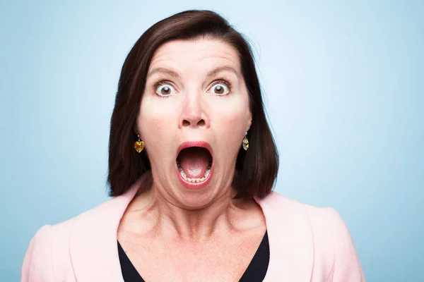 Shot of a mature woman looking shocked against a studio background.