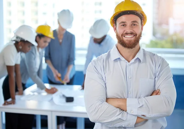 Shot of a young businessman standing with his arms crossed in an office at work.