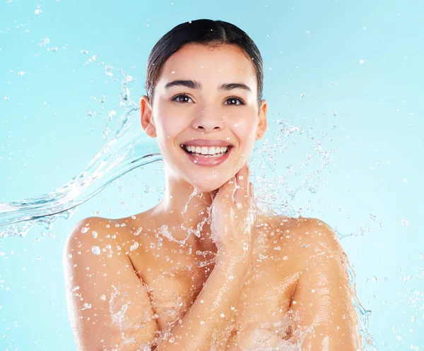 Shot of a beautiful young woman being splashed with water against a blue background.