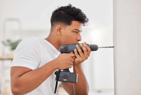 Shot of a man using a cordless drill on a wall.