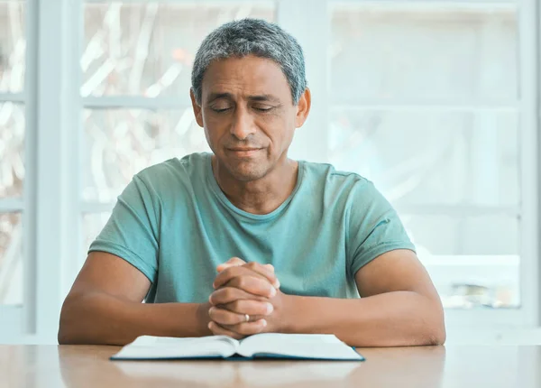 Shot of an older man having quiet prayer time at home.