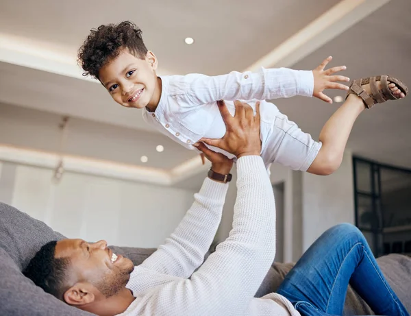 Joyful Young Dad Lying Couch Lifting Happy Excited Little Boy — Stock fotografie