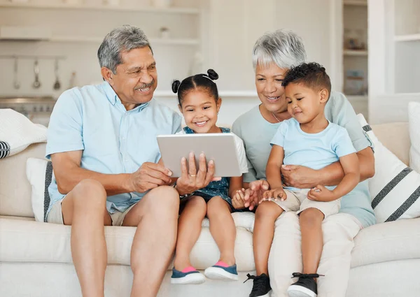 Shot Grandparents Bonding Grandchildren Using Digital Tablet Sofa Home — Stockfoto