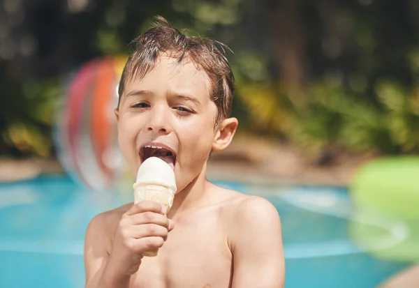 Cropped portrait of an adorable little pool eating an ice cream while sitting outside by the pool.