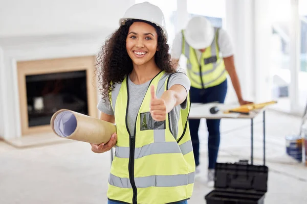 Shot of an attractive young contractor standing inside and showing a thumbs up.