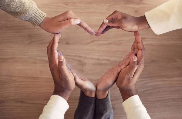 High angle shot of a group of unrecognizable businesspeople forming a heart shape with their hands.