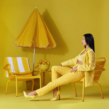 Studio shot of a young woman dressed in stylish yellow clothes against a yellow background.