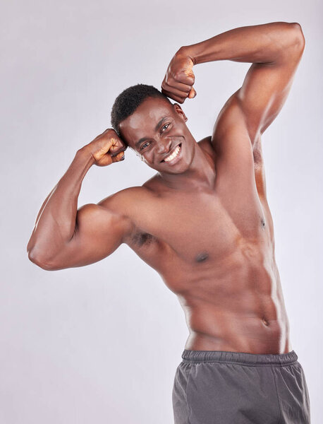 Studio portrait of muscular young man flexing his arms against a grey background.