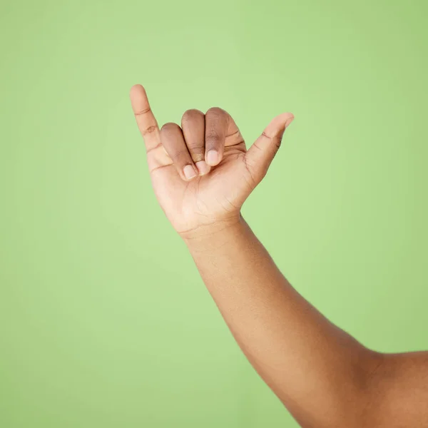 Cropped shot of a man showing a hand sign against a green background.