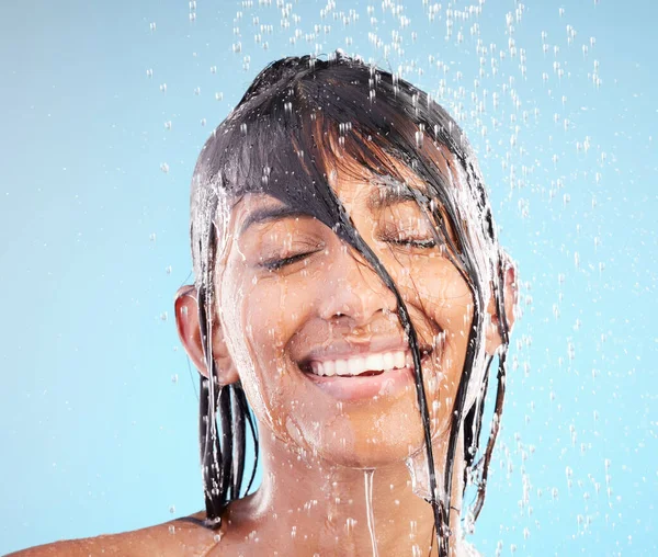 青い背景を背景にシャワーで髪を洗う若い女性のショット — ストック写真