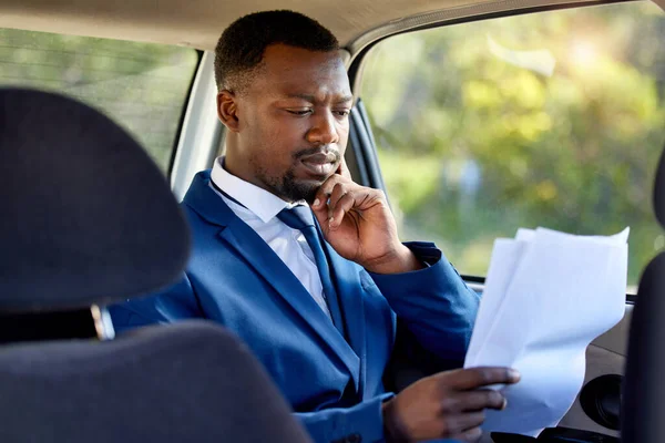 Cropped shot of a handsome businessman looking over paperwork during his morning taxi ride into work.